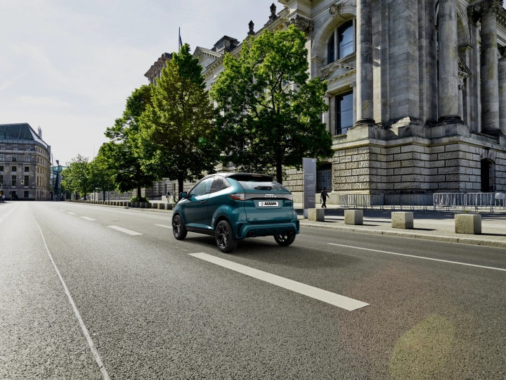 Voiture sans permis électrique Aixam roulant en ville devant un bâtiment historique