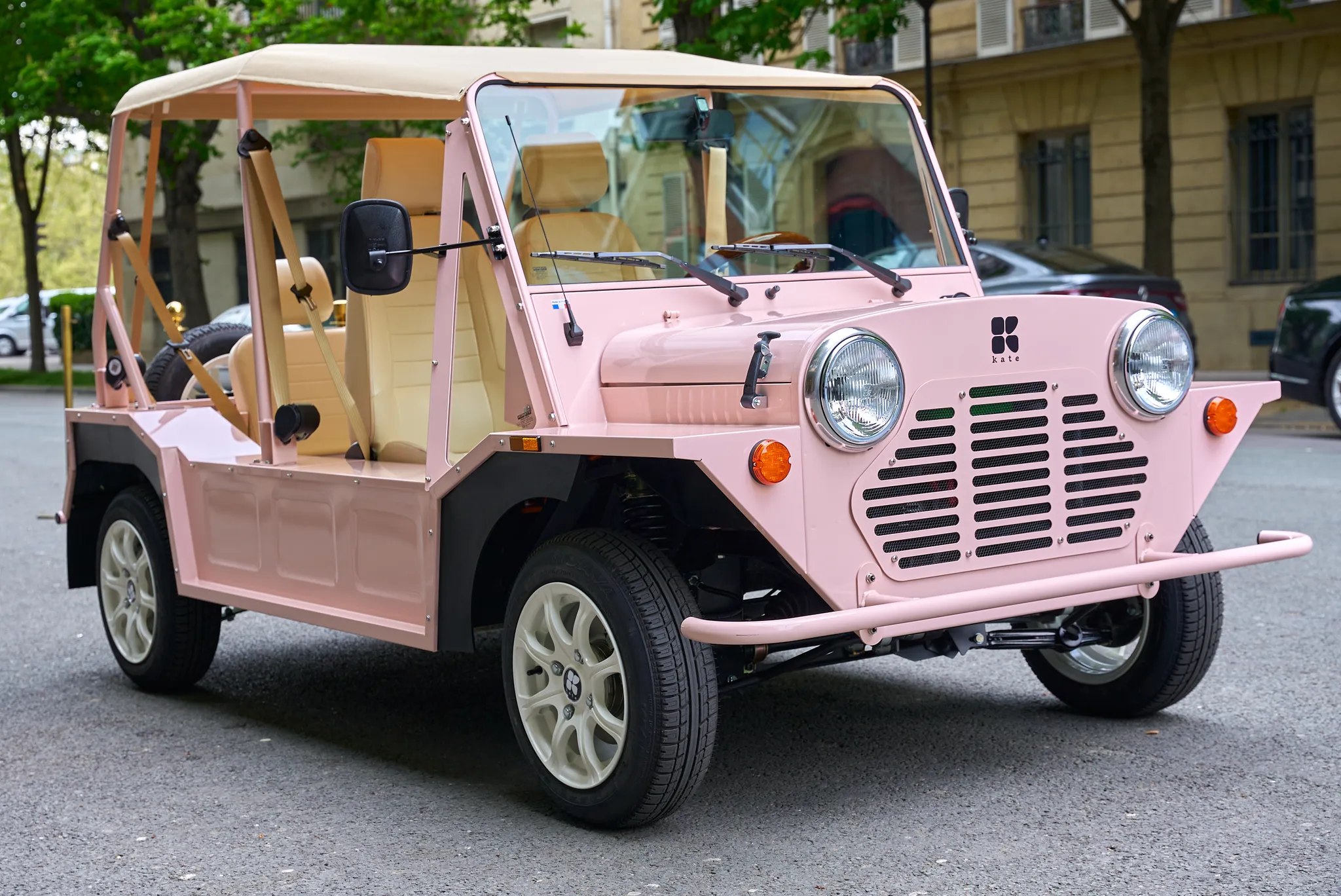 Kate voiture électrique style Mini Moke rose stationnée en milieu urbain